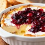 Warm baked brie dip topped with glossy cranberry sauce.